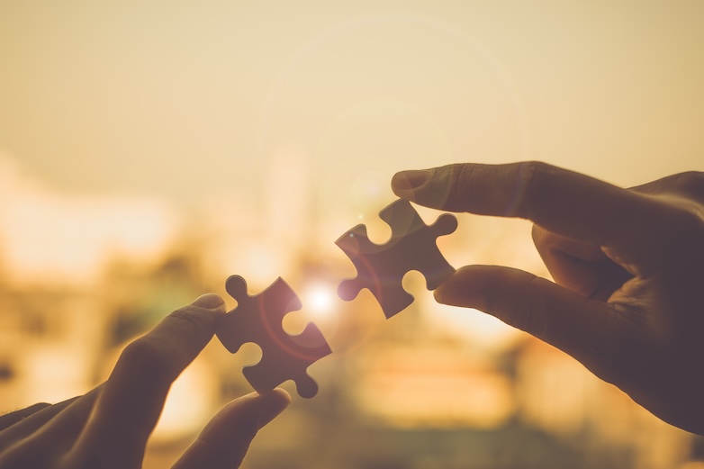 Two hands holding a jigsaw puzzle piece, symbolizing hope and unity in our mission to bring hope to those in need.